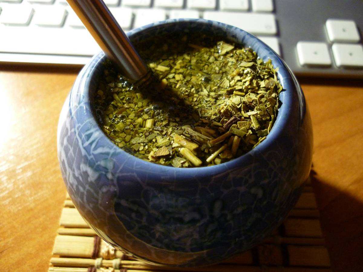 A steaming cup of lemon balm tea with fresh leaves on the side.