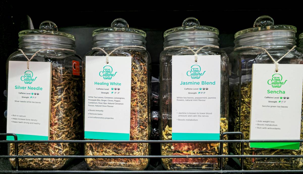 A steaming mug of lemon balm tea beside a jar of dried lemon balm leaves.