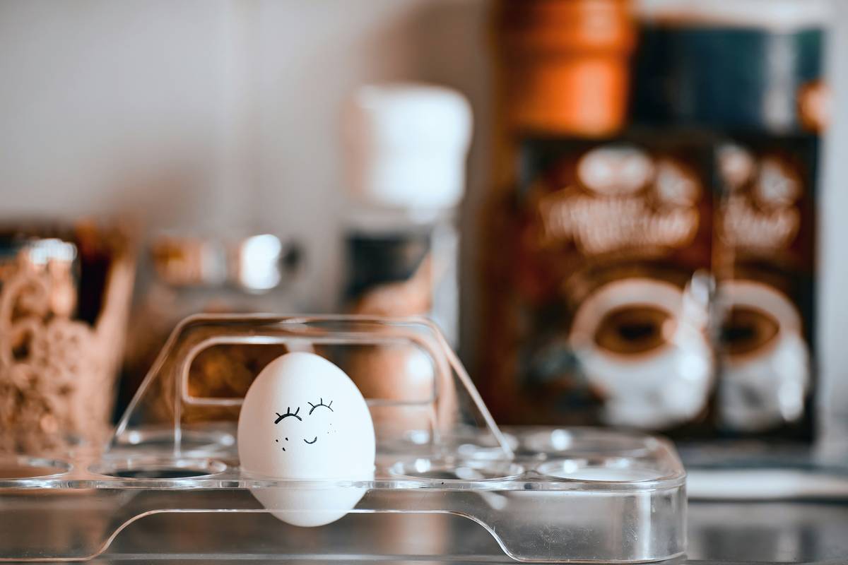 Fresh green leaves of lemon balm laid out on a wooden table next to a steaming mug of tea